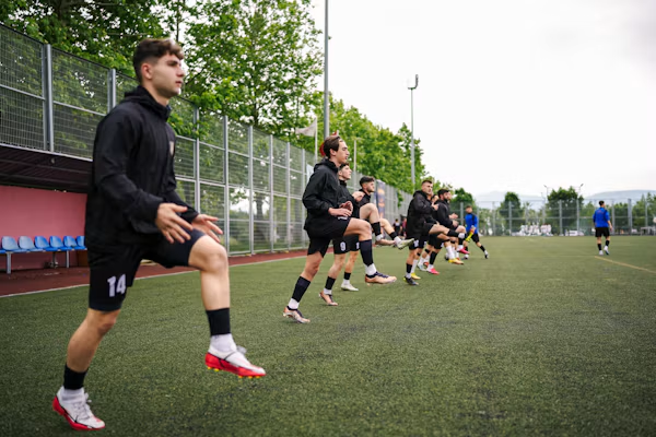 Youth players warming up in a line on a training pitch.